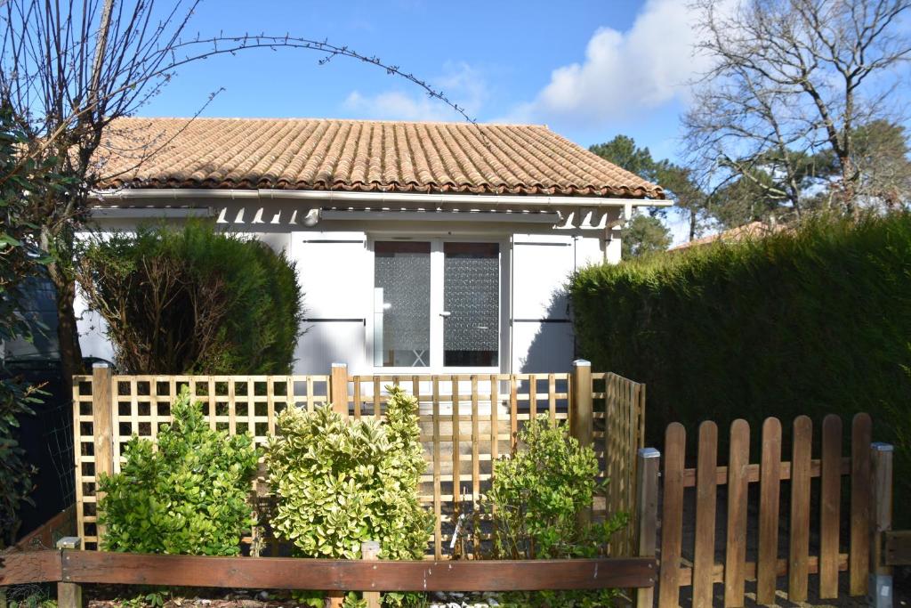 une maison blanche derrière une clôture en bois dans l'établissement La cigogne, à La Tremblade