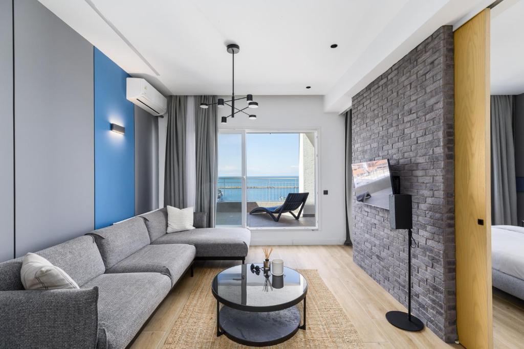 #Oddity seafront apartments في سلانيك: غرفة معيشة مع أريكة رمادية وجدار من الطوب