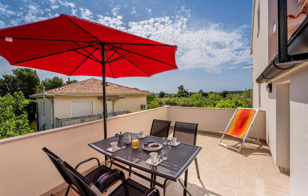 una mesa con una sombrilla roja en el balcón en Nice Apartment In Medulin With Kitchen, en Medulin