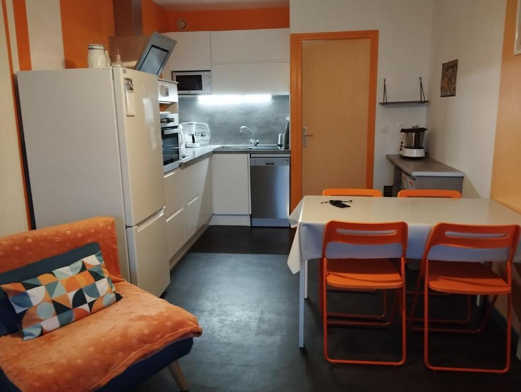 Il comprend une cuisine équipée d'un réfrigérateur blanc, d'une table et de chaises. dans l'établissement F2 La Corniche 