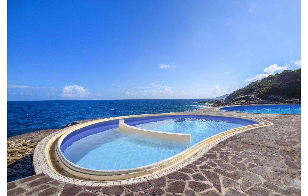 two swimming pools with the ocean in the background at 3 Bedroom Nice Apartment In Rio Marina in Rio Marina