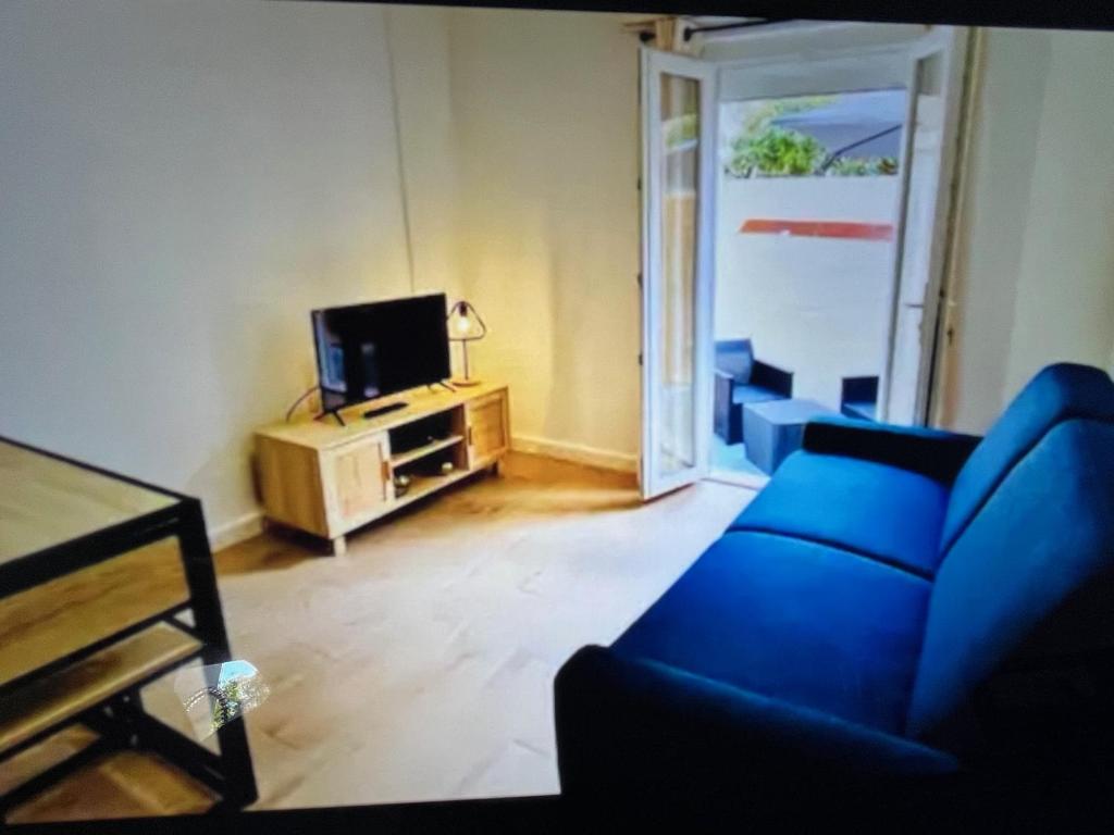 un salon avec un canapé bleu et une télévision dans l'établissement Studio climatisé aux plages 1, à Sète