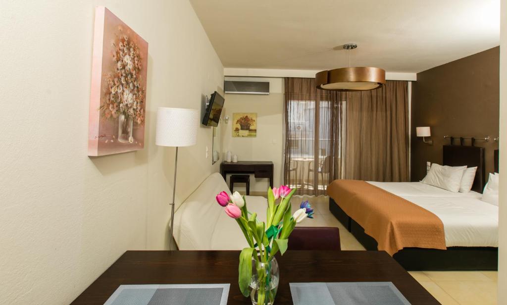 una habitación de hotel con una cama y una mesa con flores en Cosmos Hotel, en Rethymno