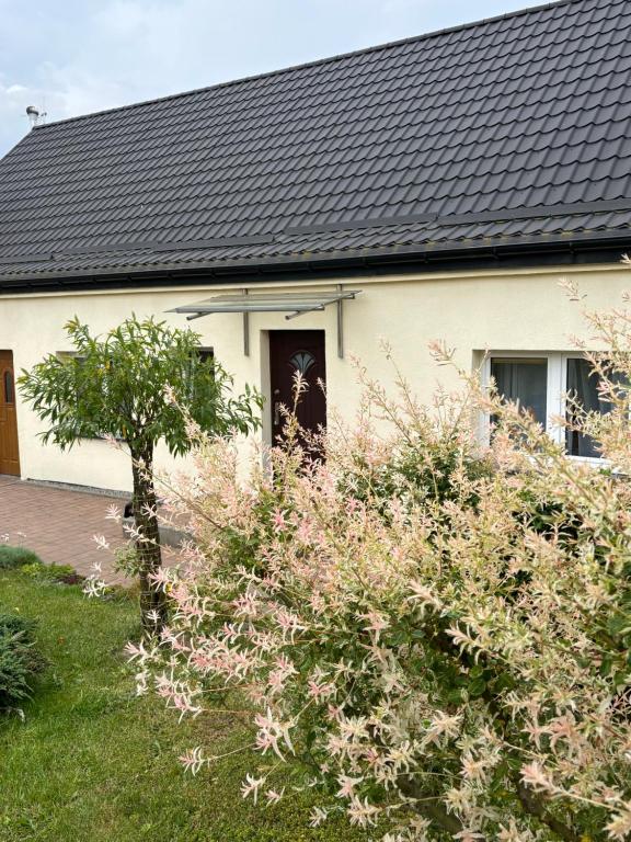 una casa blanca con techo negro en Dom Wakacyjny na Wsi Blisko Morza, en Kukinia