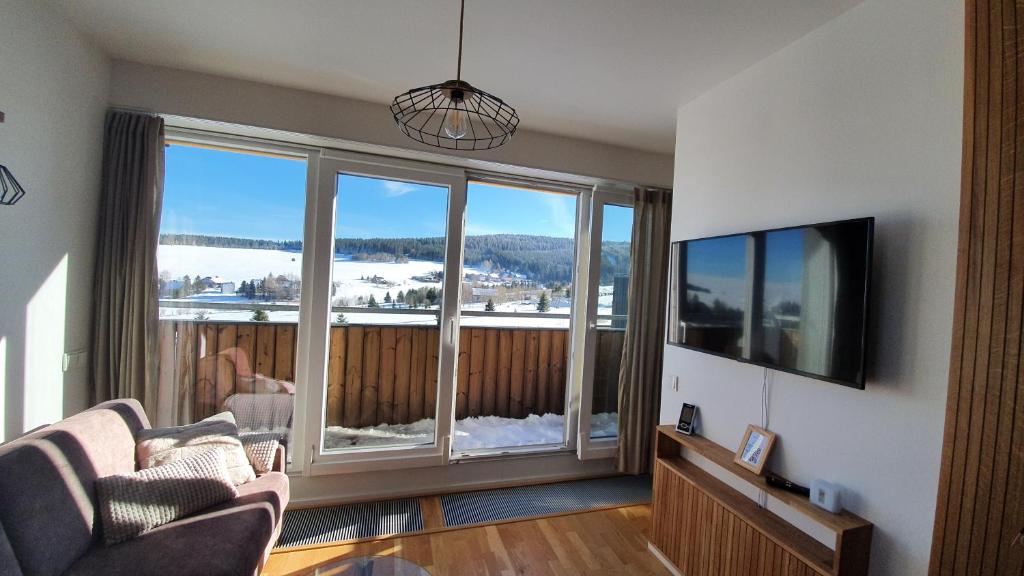 a living room with a couch and a large window at Mezonetový apartmán se dvéma balkóny a výhledem in Loučná pod Klínovcem