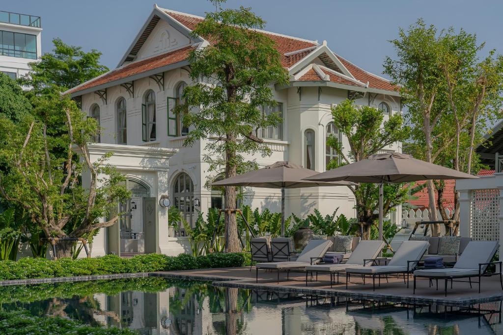 un complexe avec des chaises et des parasols à côté d'une piscine dans l'établissement Souphattra Heritage Vientiane, à Vientiane