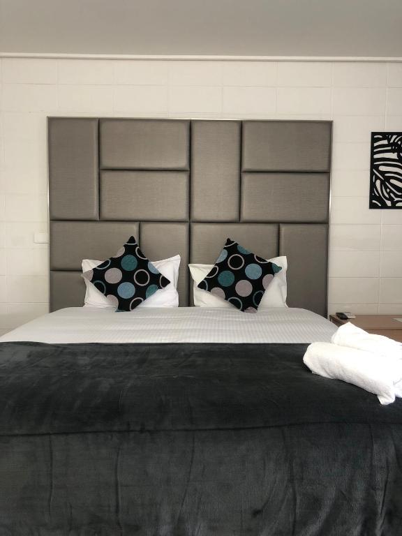 1 dormitorio con 1 cama grande con almohadas blancas y negras en Gladstone CBD Motel, en Gladstone