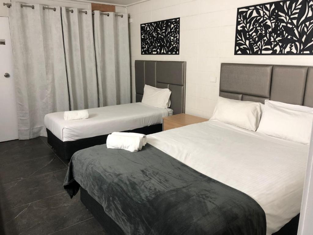 a hotel room with two beds and a table at Gladstone CBD Motel in Gladstone