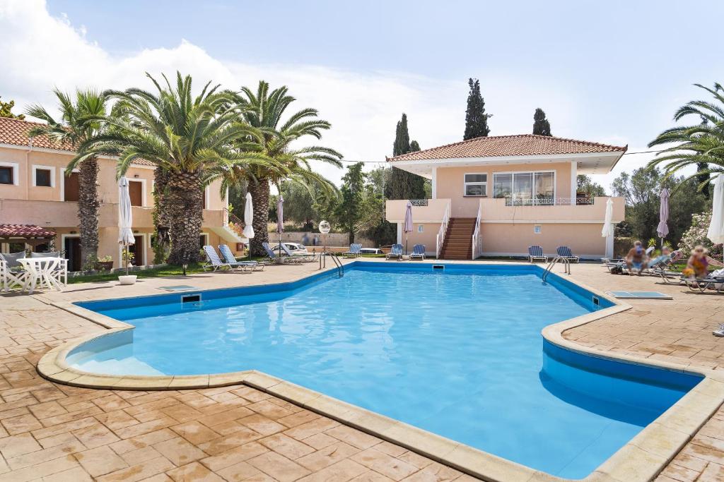 una piscina frente a una casa con palmeras en Helena Inn Kefalonia, en Cefalonia