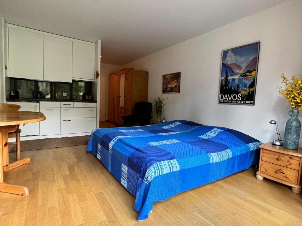 a bedroom with a blue bed and a desk at Obm See in Davos Wolfgang