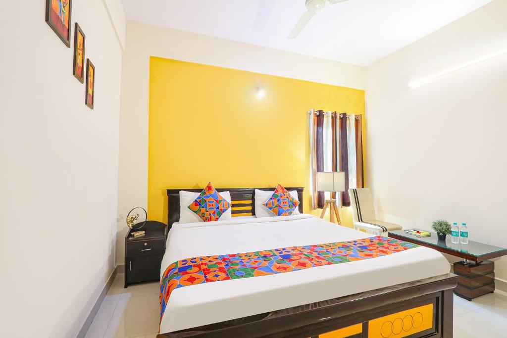 FabHotel Namaha Suites في حيدر أباد: غرفة نوم بسرير ومكتب وجدار اصفر