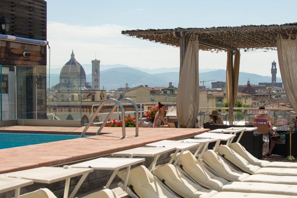 uma fila de cadeiras brancas, uma mesa e uma piscina em Hotel Kraft em Florença