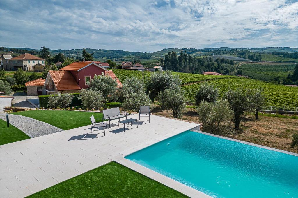 a swimming pool with two chairs and a house at Casa do Alambique - Douro in Armamar