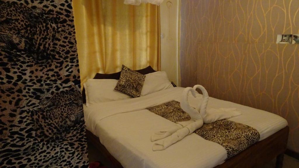 a bedroom with two beds with white sheets and pillows at Wooden Knee Cottages Nanyuki in Nanyuki
