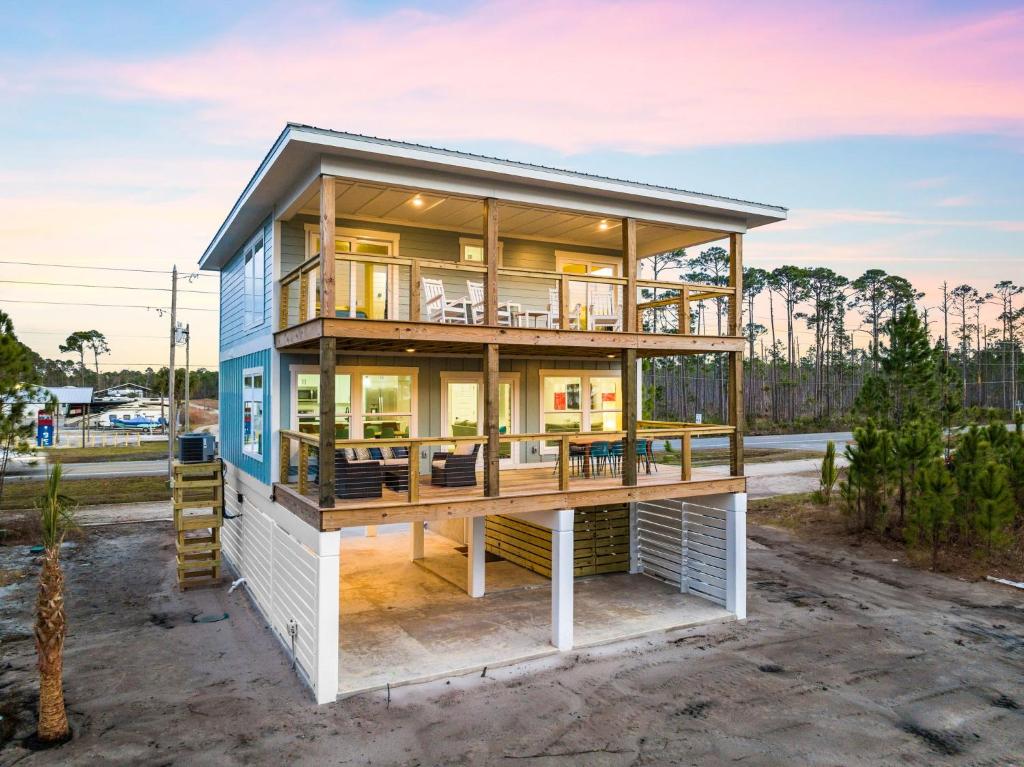 a house with a wrap around deck and glass at The Bay House-Bayfront serenity, stunning sunsets in Ward Ridge