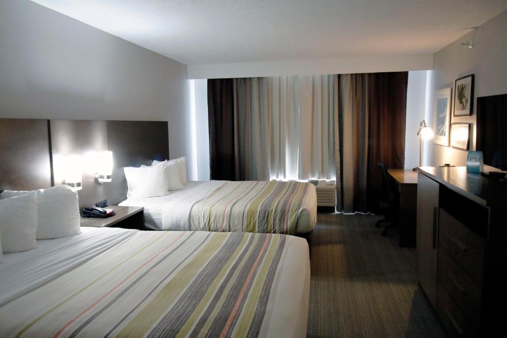 ein Hotelzimmer mit zwei Betten und einem Schreibtisch in der Unterkunft Country Inn &amp; Suites by Radisson, Council Bluffs, IA in Council Bluffs