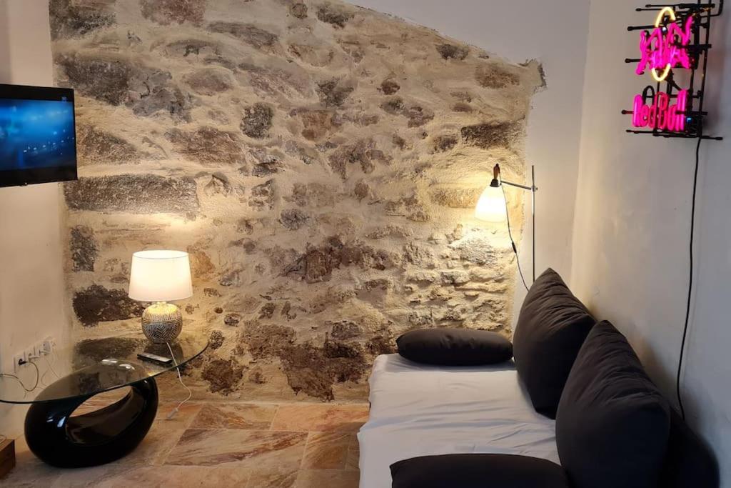 - un salon avec un canapé blanc et un mur en pierre dans l'établissement Superbe appartement au cœur du village, à Marseillan