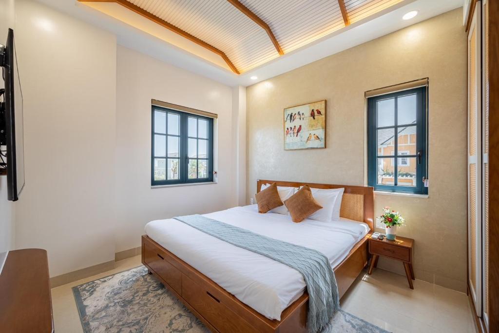 a bedroom with a bed and two windows at AnnA Villa - Novaworld Phan Thiết in Bình Tú