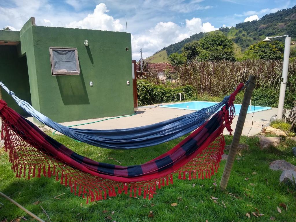 una hamaca frente a una casa con piscina en Quarto Pérola simples, en Gonçalves