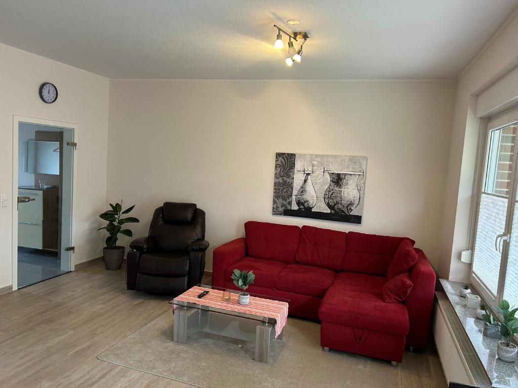 sala de estar con sofá rojo y mesa en Ferienhaus Seeidylle, en Geeste