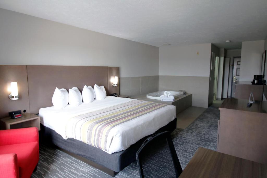 ein Hotelzimmer mit großem Bett und Badewanne in der Unterkunft Country Inn &amp; Suites by Radisson, Council Bluffs, IA in Council Bluffs