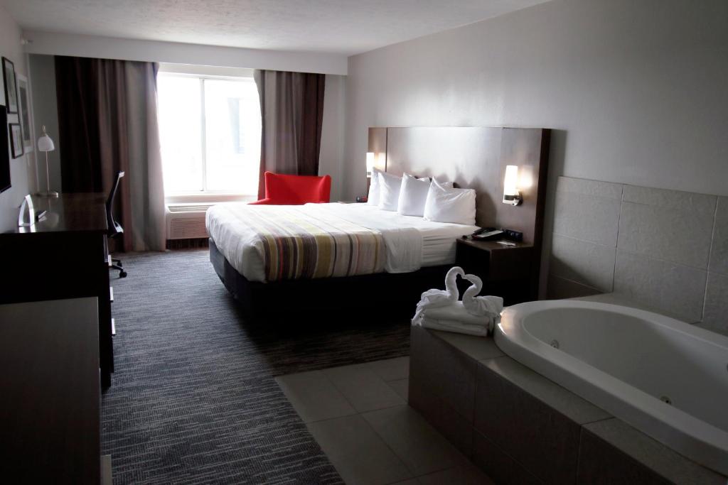 ein Hotelzimmer mit einem Bett und einer Badewanne in der Unterkunft Country Inn &amp; Suites by Radisson, Council Bluffs, IA in Council Bluffs