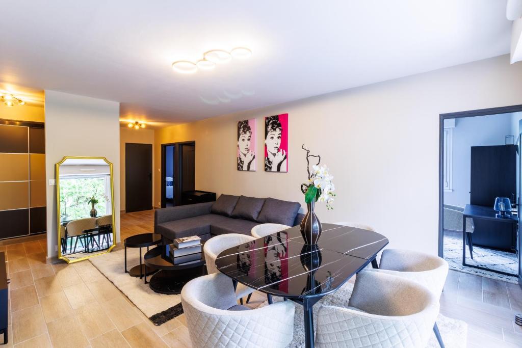 Una sala de estar con un sofá, una mesa y sillas. en Appartement moderne près de Genève, en Ferney-Voltaire