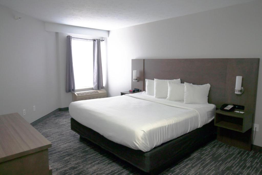 ein Hotelzimmer mit einem großen Bett mit weißen Laken in der Unterkunft Country Inn &amp; Suites by Radisson, Council Bluffs, IA in Council Bluffs