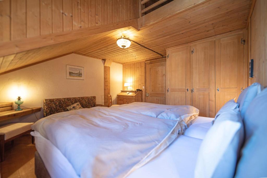 um quarto com uma grande cama branca com paredes de madeira em Ferienwohnungen im Boutique-Hotel Alpenrose em Schönried