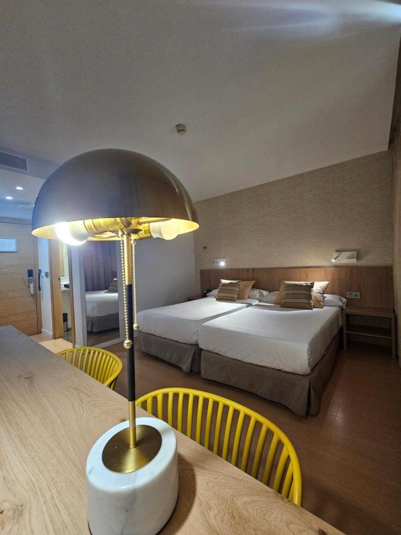Habitación de hotel con 2 camas y mesa con lámpara en Daniya Alicante, en Alicante