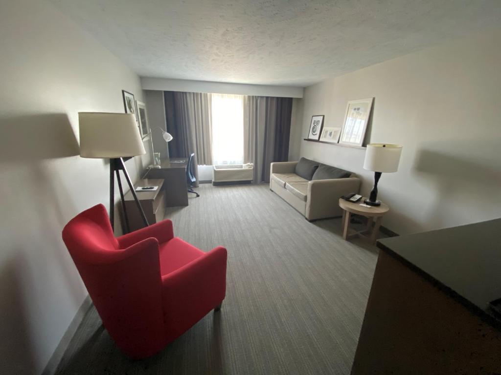 Habitación de hotel con silla roja y sofá en Country Inn & Suites by Radisson, Council Bluffs, IA en Council Bluffs