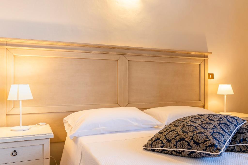 a bed with a wooden headboard in a bedroom at Hotel Corallo in Castiglioncello