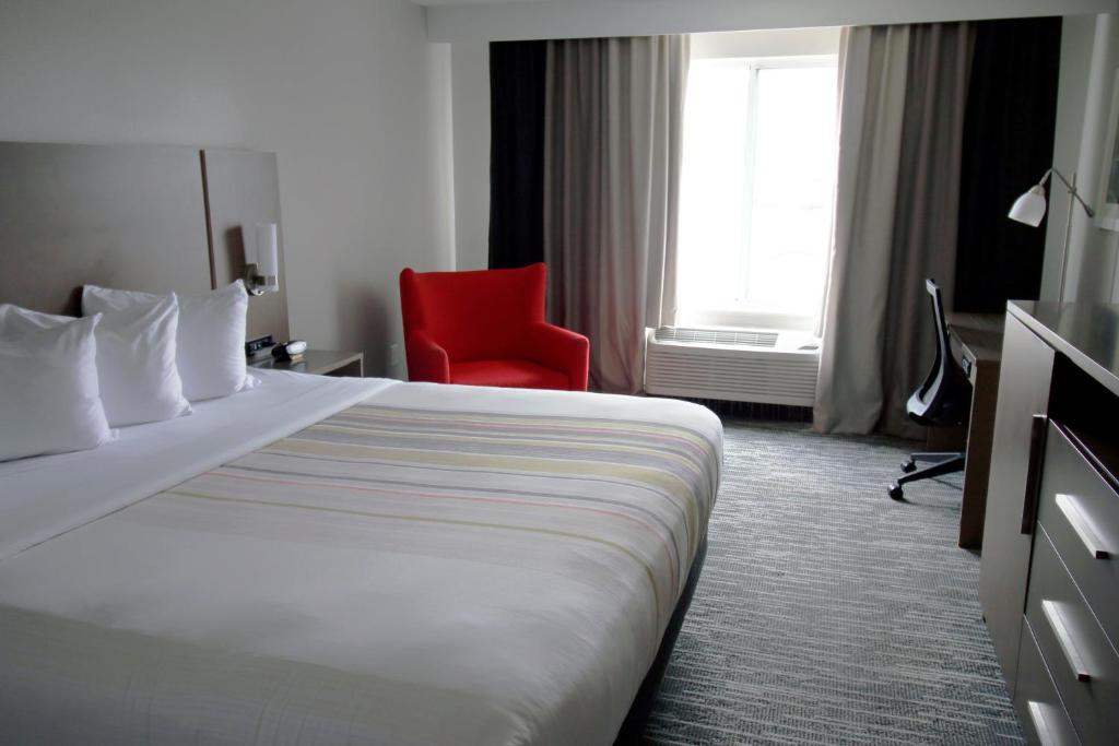 ein Hotelzimmer mit einem Bett und einem roten Stuhl in der Unterkunft Country Inn &amp; Suites by Radisson, Council Bluffs, IA in Council Bluffs