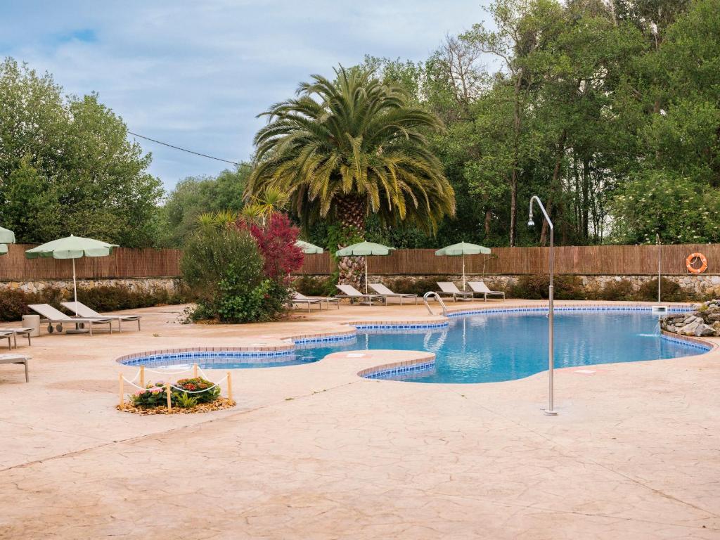 una gran piscina con sillas y sombrillas en wecamp Cudillero, en El Pito