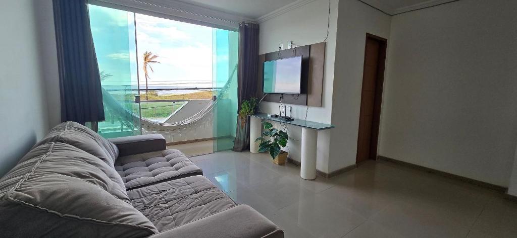 a living room with a couch and a large window at Apartamento Vista para Mar in Guriri
