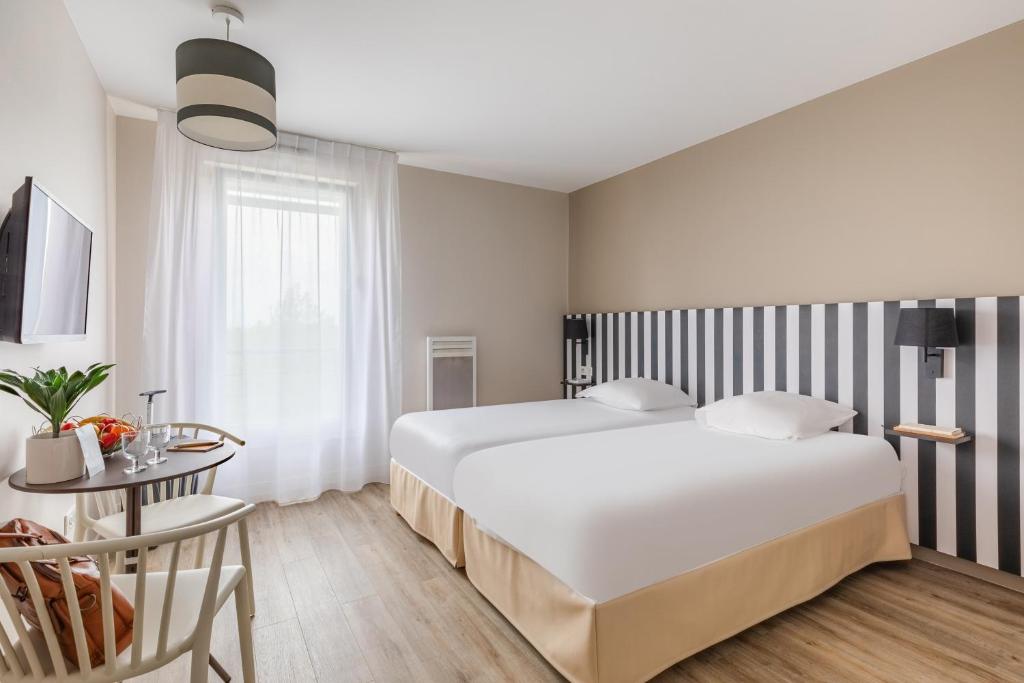 ein Schlafzimmer mit einem großen weißen Bett und einem Tisch in der Unterkunft Appart'City Classic Reims Parc des Expositions in Reims