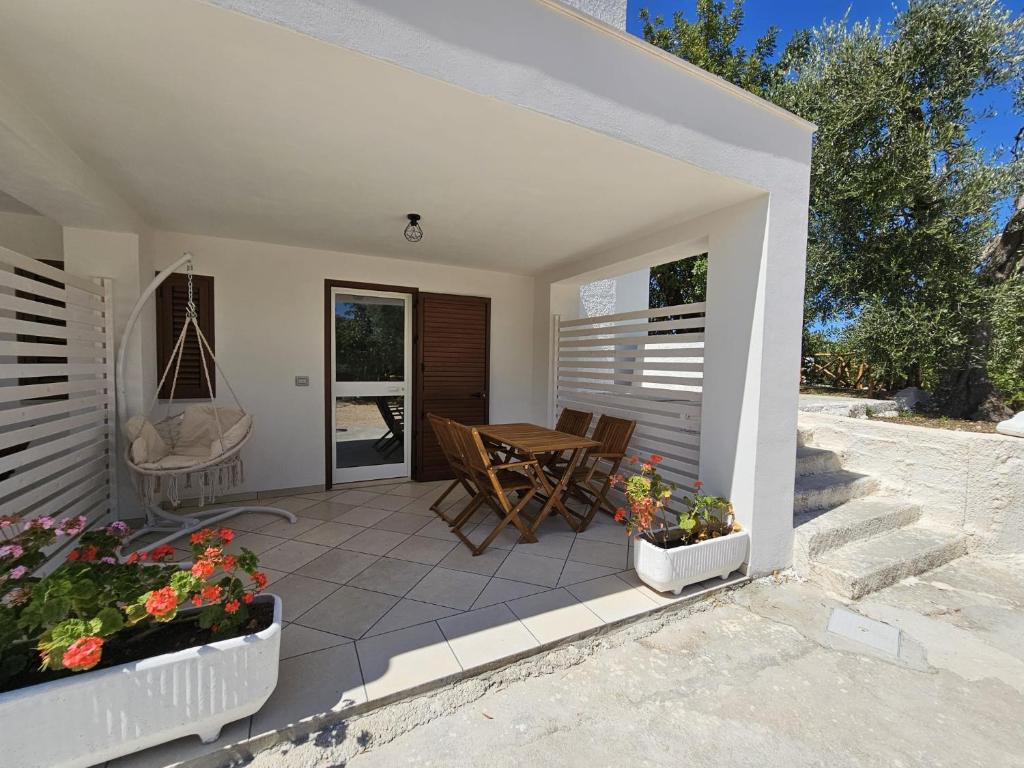 een terras met een tafel, stoelen en bloemen bij Le Carrube Rooms in Peschici