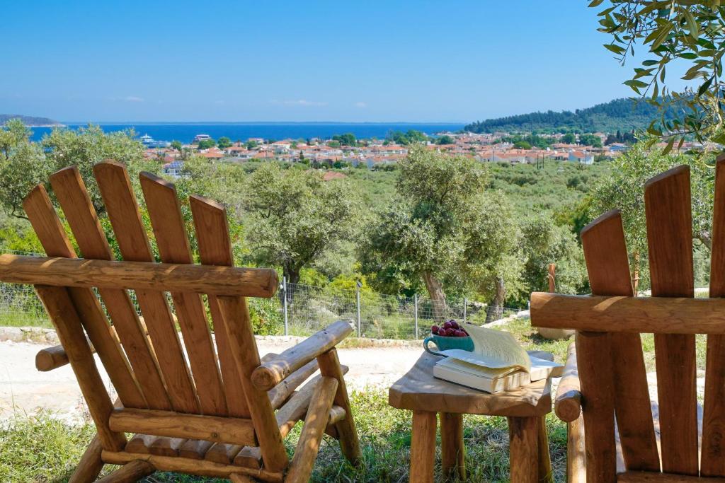 duas cadeiras de madeira sentadas ao lado de uma mesa com livros em Helicon Luxury Villas em Limenas