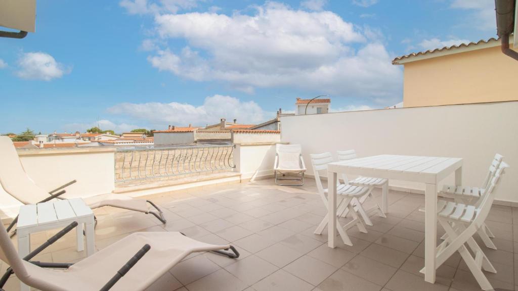 Un patio con una mesa y sillas en un tejado. en La Casa di Anita, en Orosei
