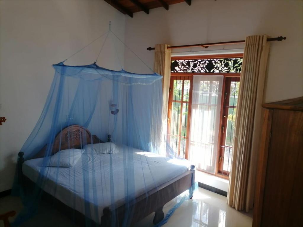 a bedroom with a canopy bed and a window at Paradise villa aluthgama in Aluthgama