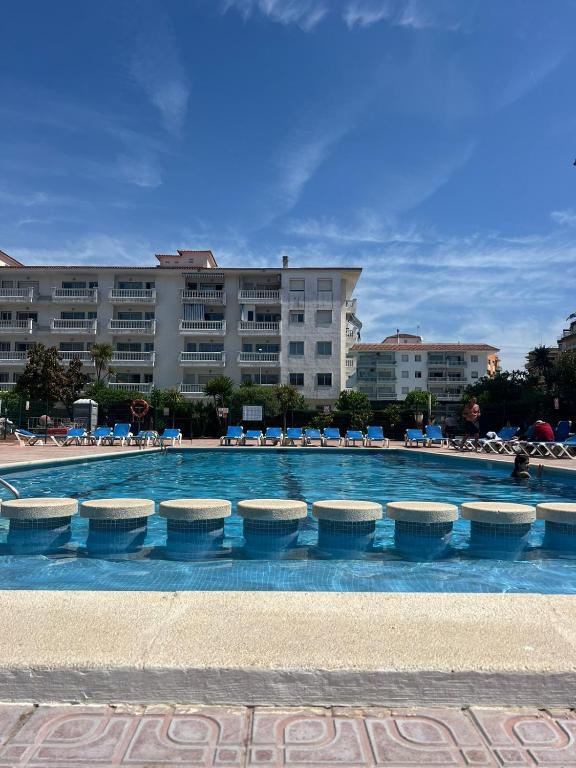 a swimming pool with chairs and a building in the background at APCOSTAS Els Pins Lotus in Blanes