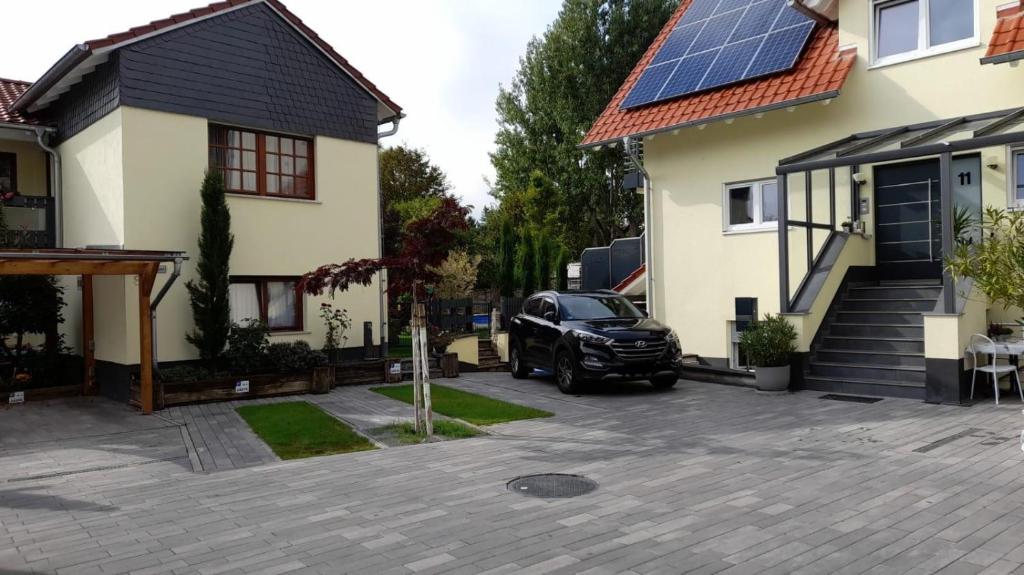 a black car parked in front of a house with solar panels at Am Dollespark in Bodenheim