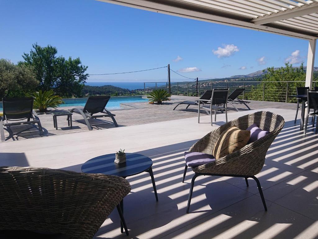 une femme assise sur une chaise sur un patio dans l'établissement Villa Cassis Vue mer et vignes, à Cassis