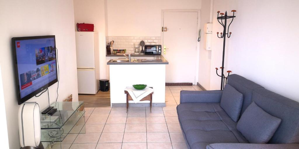 un salon avec un canapé bleu et une cuisine dans l'établissement Le California, à Cagnes-sur-Mer