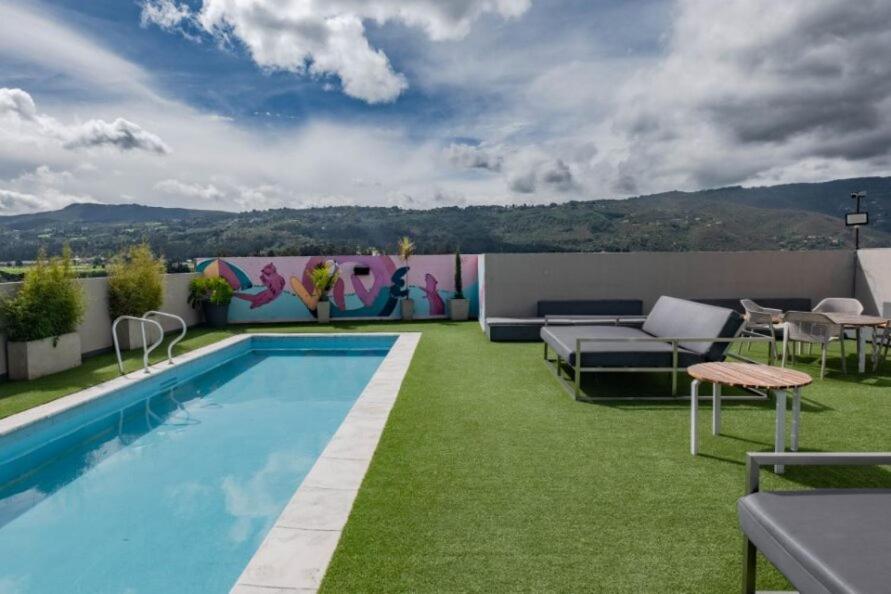 a backyard with a swimming pool and green grass at UMA Suites Chia in Chía