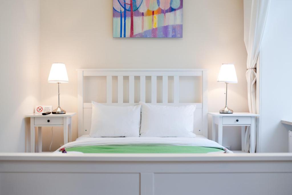 ein weißes Schlafzimmer mit einem Bett und zwei Lampen in der Unterkunft Danylo Inn in Lwiw