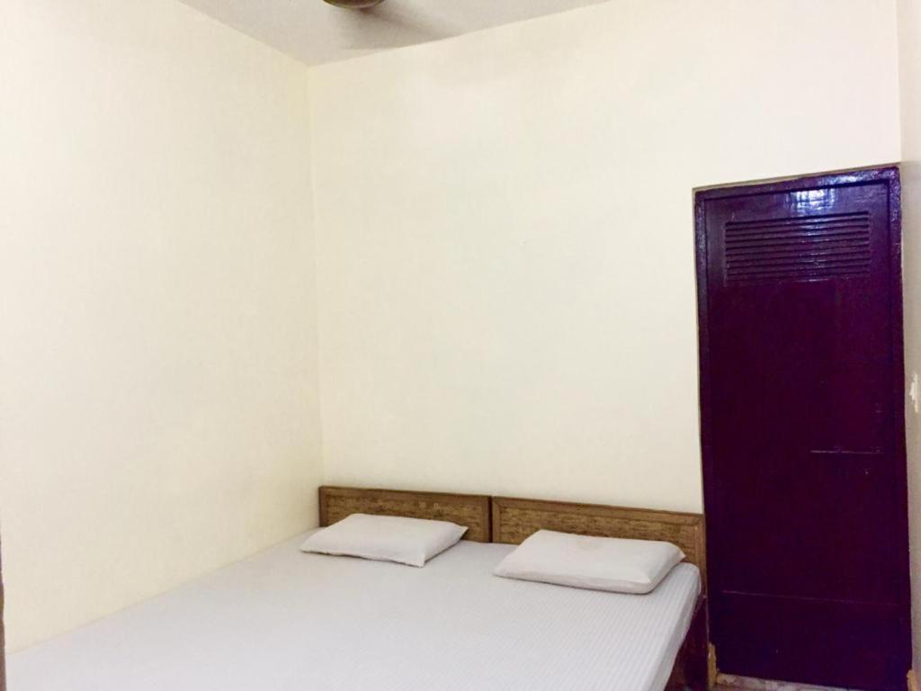 a small room with a bed and a purple door at GRG Shanti Guest House Varanasi Near Manikarnika Ghat in Varanasi