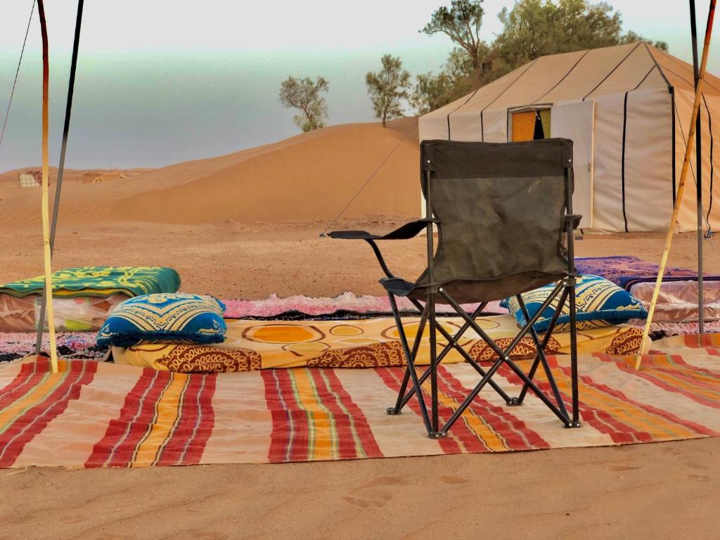 krzesło siedzące na dywanie na pustyni w obiekcie M'Hamid Budget Lodge w mieście Mhamid