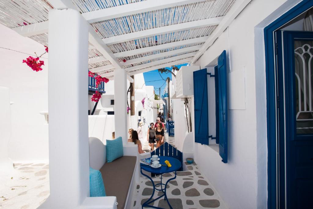 um passadiço com portas e mesas azuis num edifício branco em Eleanna's Mykonos em Míconos