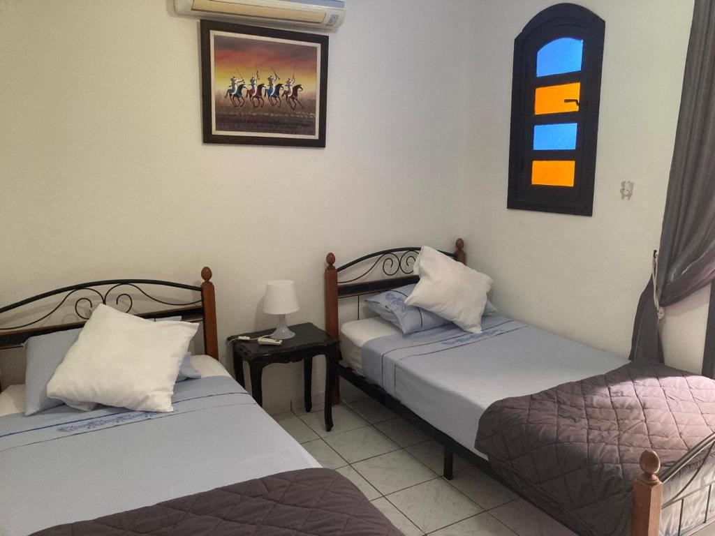 馬拉喀什的住宿－RIAD Lalla Aicha-Qariya Siyahia Marrakech，一间卧室配有两张床和一张带台灯的桌子